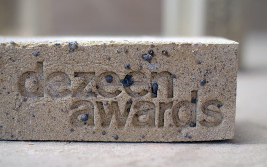 Trophée des Dezeen Awards en argile jaune, avec le texte « dezeen awards » gravé
